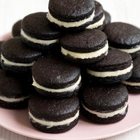 Stack of chocolate cookies with white filling on a pink plate