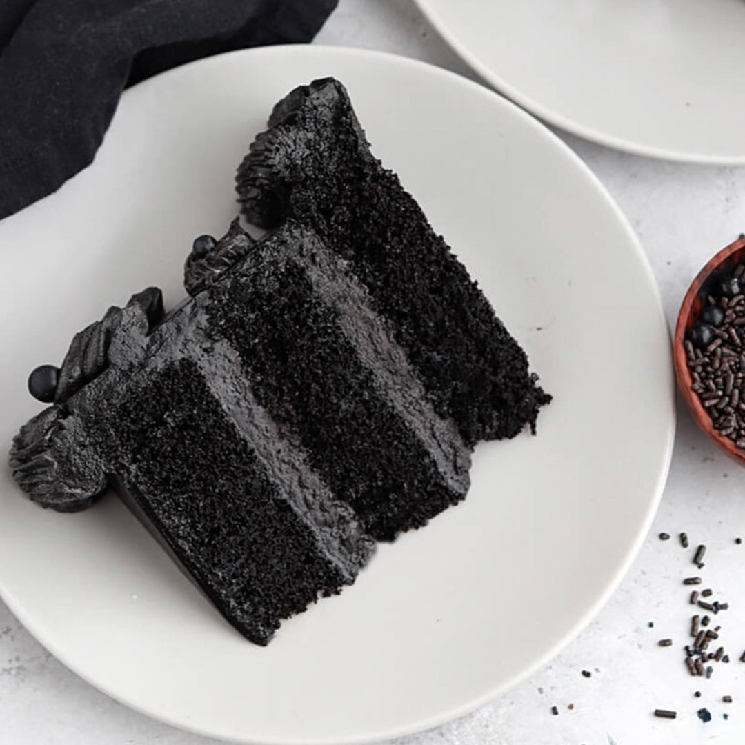Slice of black cake on a white plate with a white background