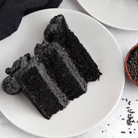 Slice of black cake on a white plate with a white background