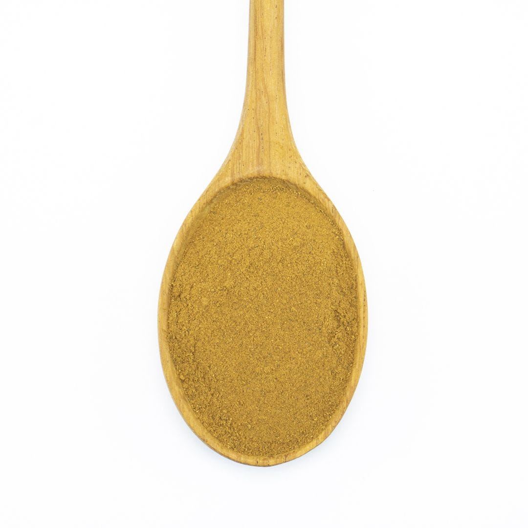 A wooden spoon filled with ground cinnamon spice.
