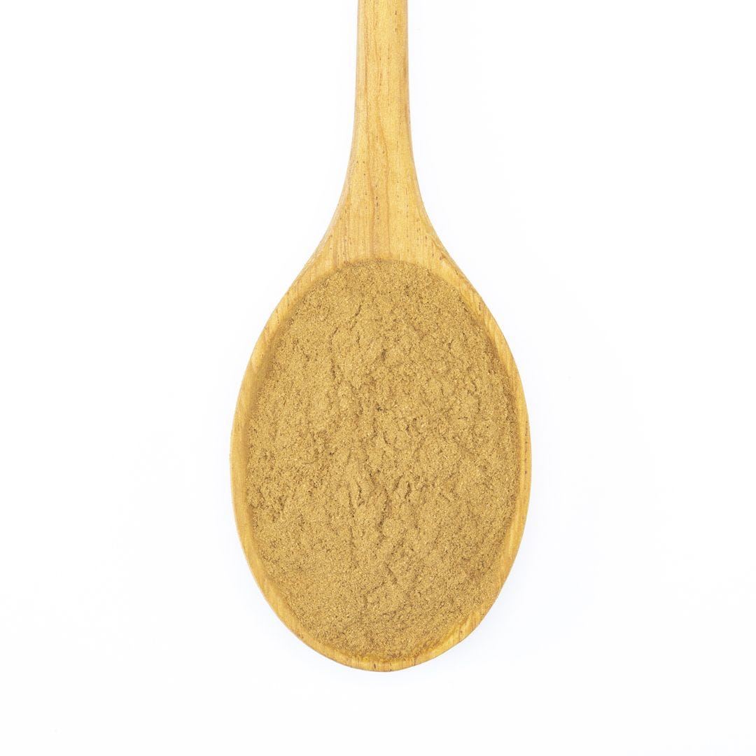 Ground cinnamon spice on a wooden spoon against a white background.