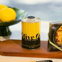 Can of olive oil on a wooden cutting board with lemons in the background