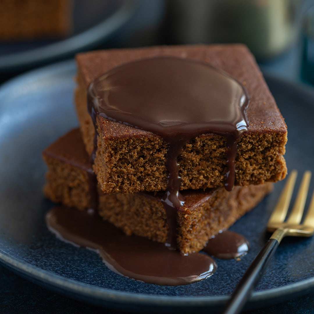 Stack of chocolate cake with drizzle on a blue plate with a fork
