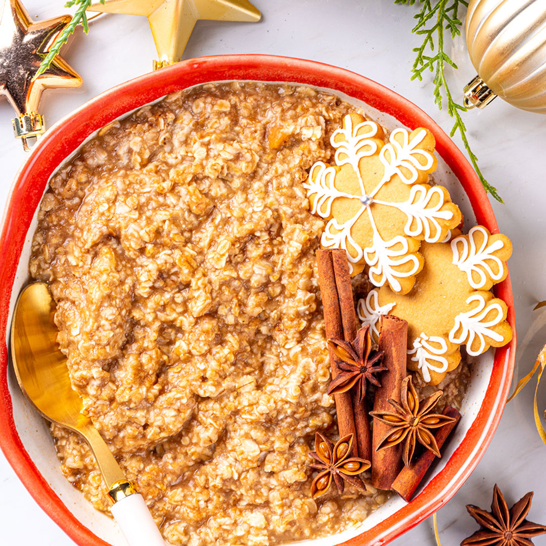 Bowl of oatmeal with decorative cookies and spices on a festive background